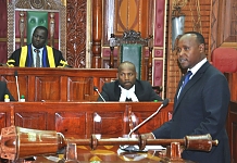Hon Peter Mathuki, Chair of the Committee on Legal Rules and Privileges presents the Report to an attentive House as Senior Clerk Assistant, Alfred Tugume and Speaker, Rt Hon Daniel F. Kidega pay attention