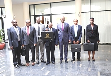 The Deputy Minister, Foreign Affairs and International Co-operation, United Republic of Tanzania, Dr Damas Ndumbaro (centre) holds aloft the briefcase containing the EAC Budget Speech moments before delivery.  He is flanked on left by Deputy Minister for