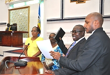 Hon Jean Marie Muhirwa takes the Oath administered by the EALA Senior Clerk Assistant, Stephen Mugume as Members, Hon Emerence Bucumi (centre) and Hon Judith Pareno (left) look on
