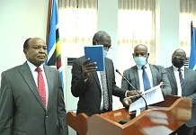 Hon James Kakooza takes the Oath administered by the EALA Deputy Clerk, Alfred Tugume as Members, Hon Adam Kimbisa and Hon Dr. Ngwaru Maghembe look on